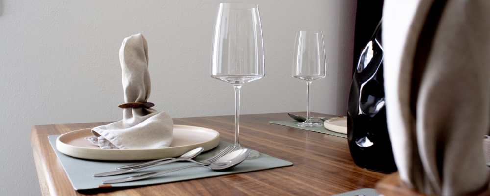 Angerichteter Dinnertisch mit Weingläsern, Servietten, Tellern und Besteck.